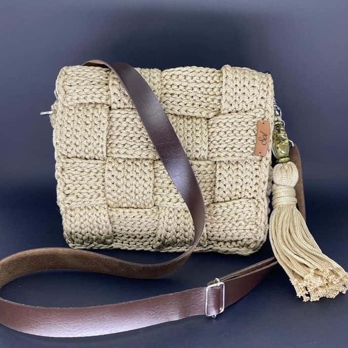 Bolsa Atenas cru em trançado de crochê, com tassel com miçanga e alça tipo couro marrom