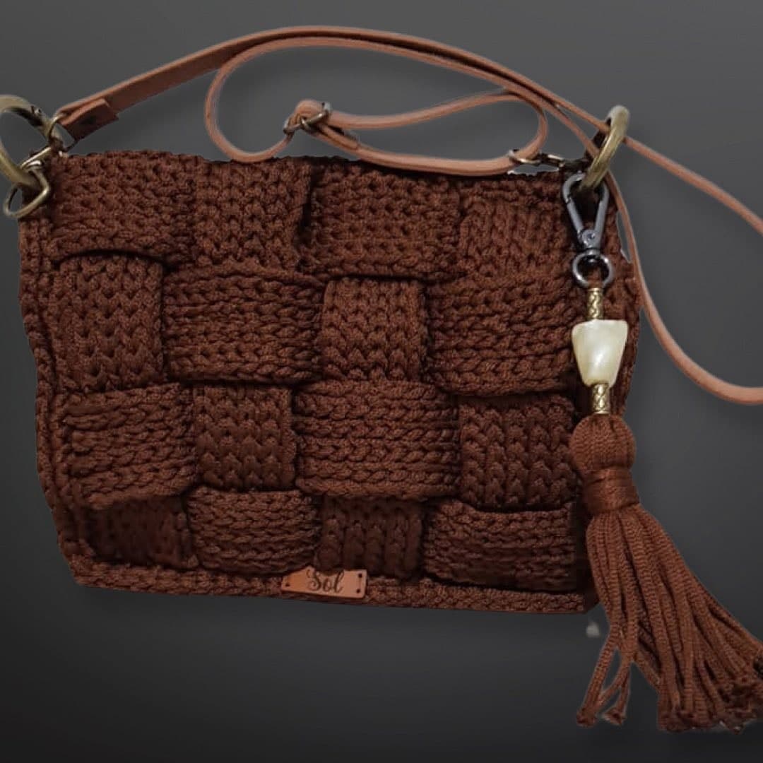 Bolsa Atenas marrom em trançado de crochê, com tassel e alça tiracolo tipo couro
