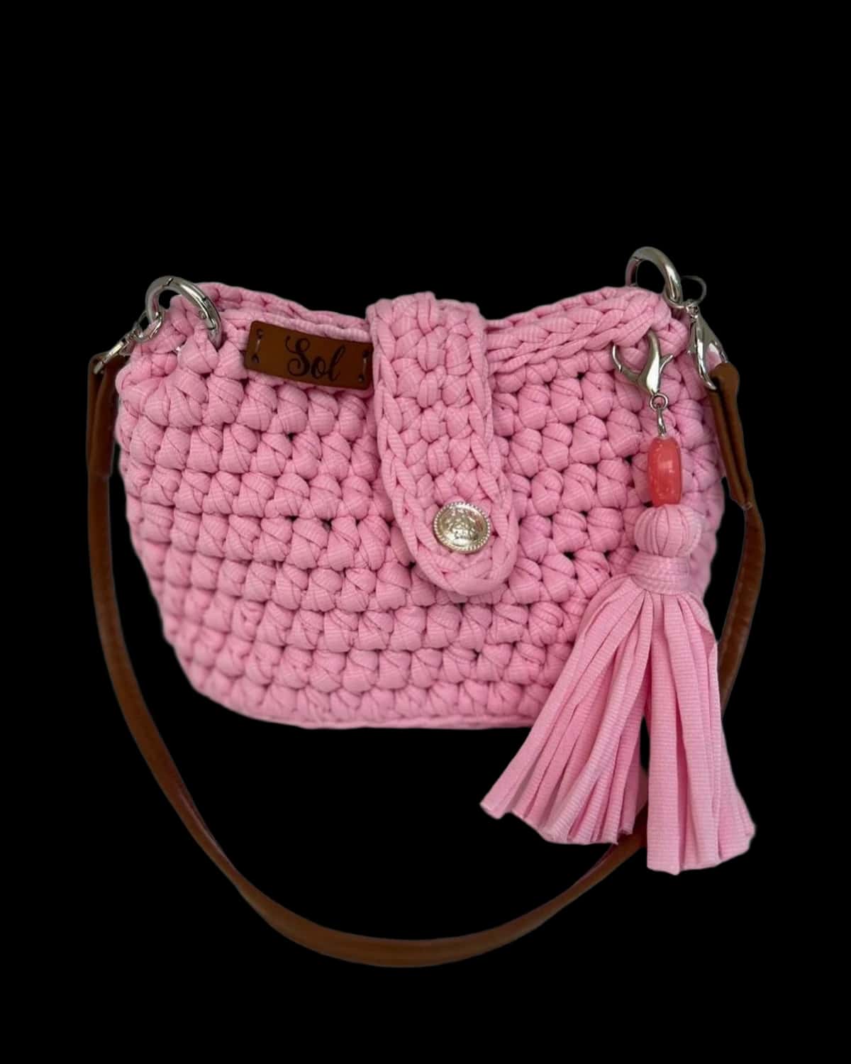 Bolsa infantil rosa com tassel e alça tipo couro marrom, foto de catálogo em fundo neutro