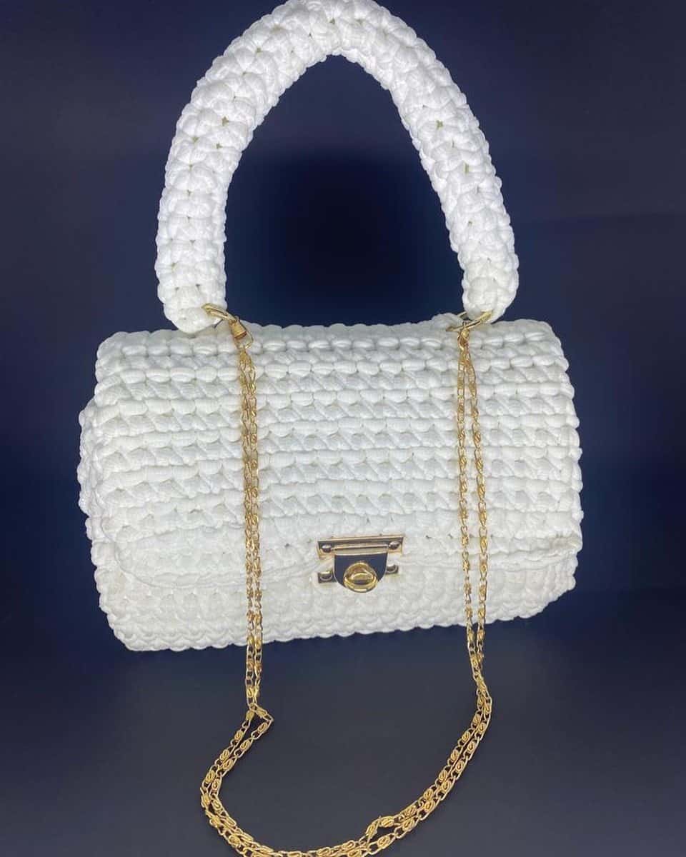 Bolsa Luxemburgo branca em formato baú, com alça de mão em crochê, fecho e corrente dourados