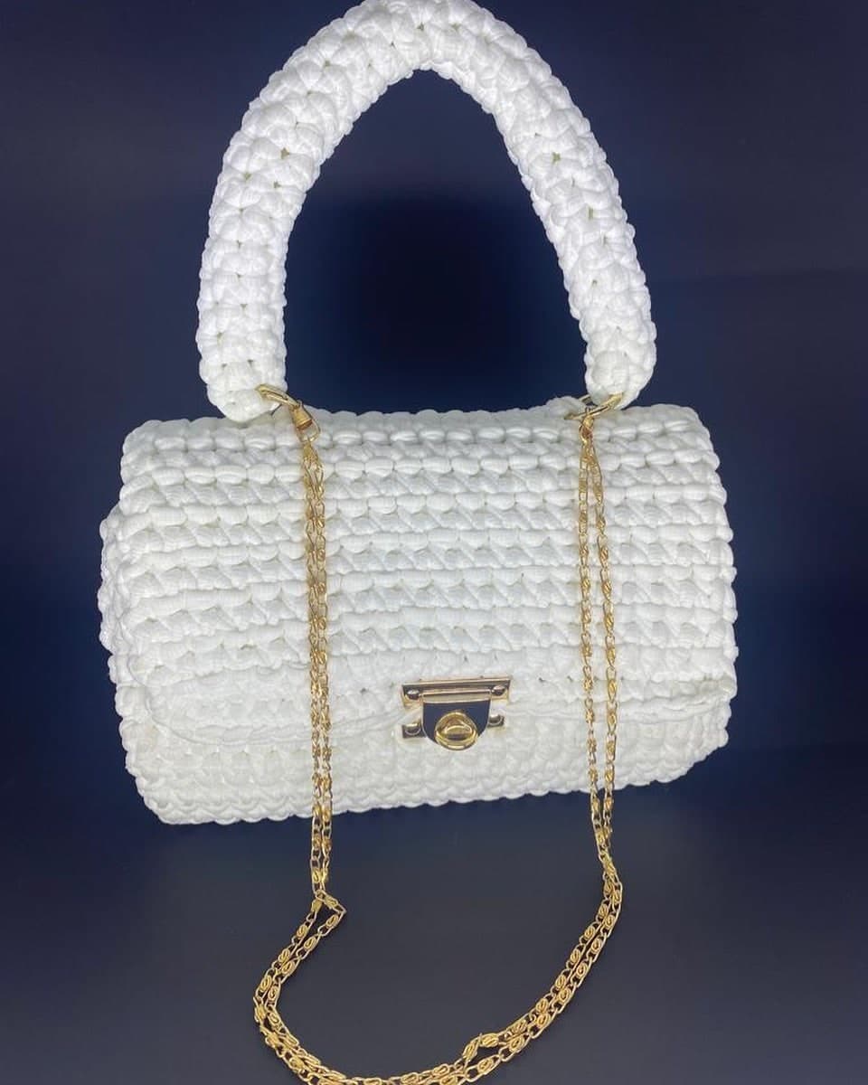 Bolsa Luxemburgo branca em formato baú, com alça de mão em crochê, fecho e corrente dourados
