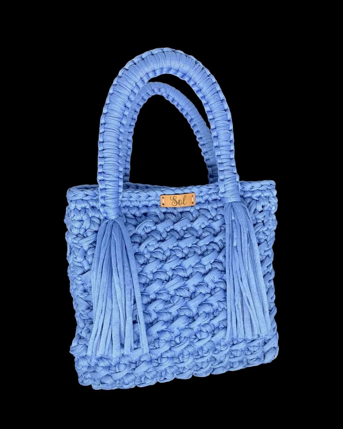 Bolsa Nice azul-céu em crochê de fio de malha, com alças de macramê e franjas nas laterais, foto de catálogo em fundo neutro