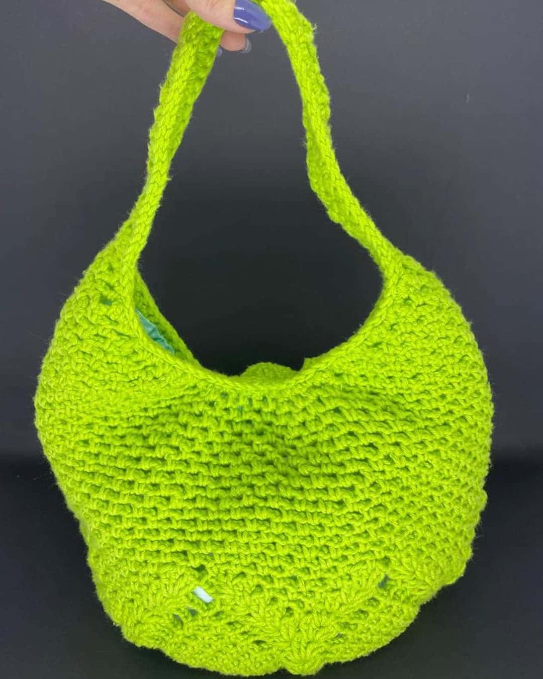 Bolsa Sauípe verde-limão em crochê de barbante, segurada pela alça