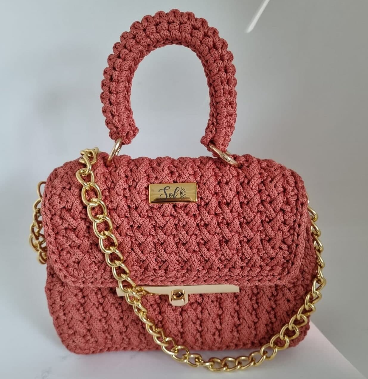 Bolsa Singapura coral com alça de mão em crochê, fecho dourado e corrente dourada de elos grandes