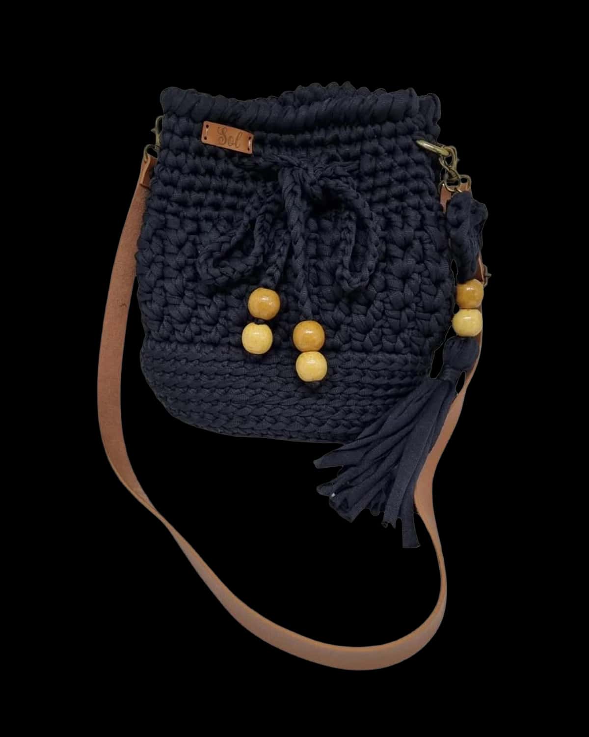 Bolsa saco Viena azul-marinho com contas de madeira, tassel e alça tipo couro caramelo, foto de catálogo em fundo neutro
